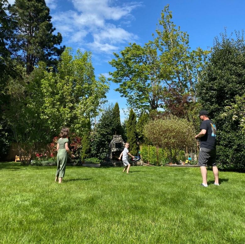 A man and children play frisbee in a yard.