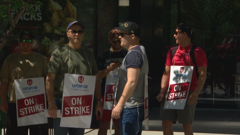 A group of people wear sandwich boards bearing the name of their union.