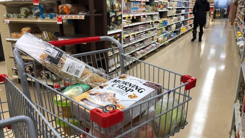 A grocery store shopping cart holding various food items. 