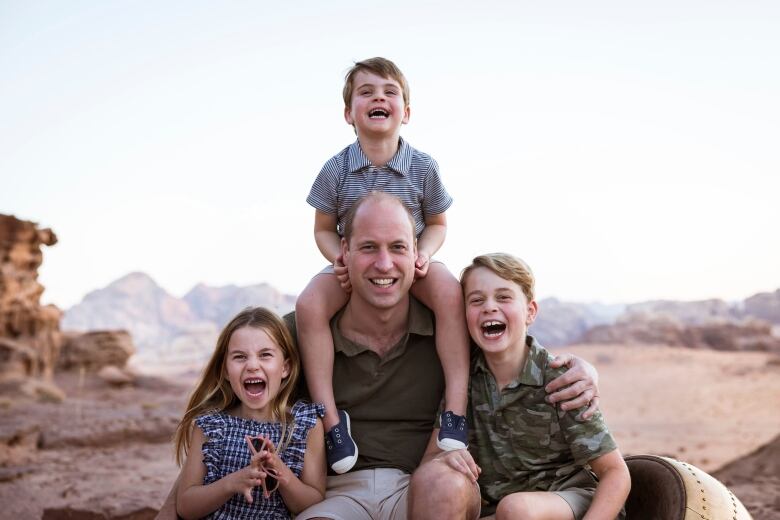 A man sits with three children.