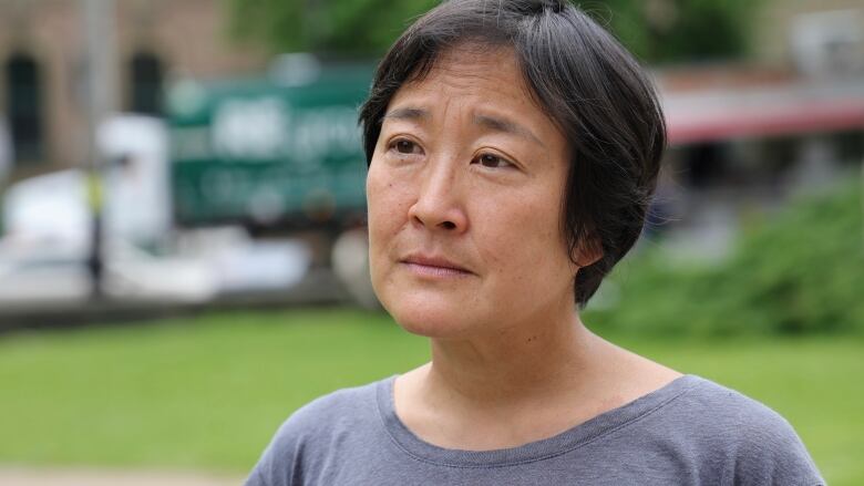 An Asian women with short hair is seen wearing a periwinkle t shirt