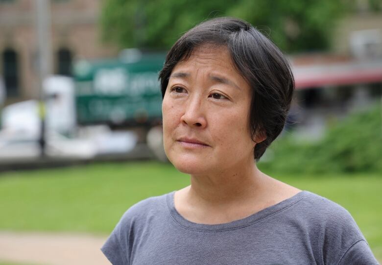 An Asian women with short hair is seen wearing a periwinkle t shirt