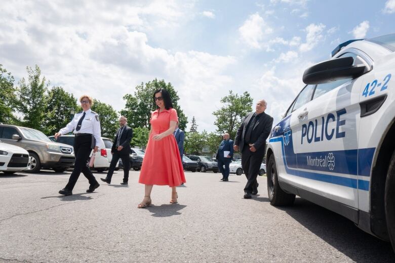 Montreal Mayor Valrie Plante walks by a Montreal police vehicle in a parking lot, alongside Montreal Police interim director Sophie Roy.