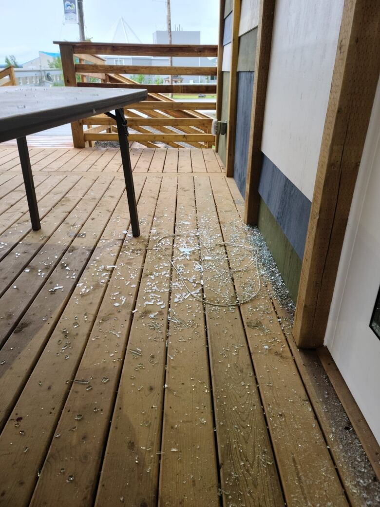 A table on a porch outside of a building with shattered glass all around it. 