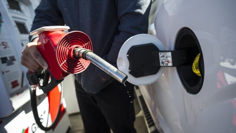 A gas pump pumps fuel into a car.