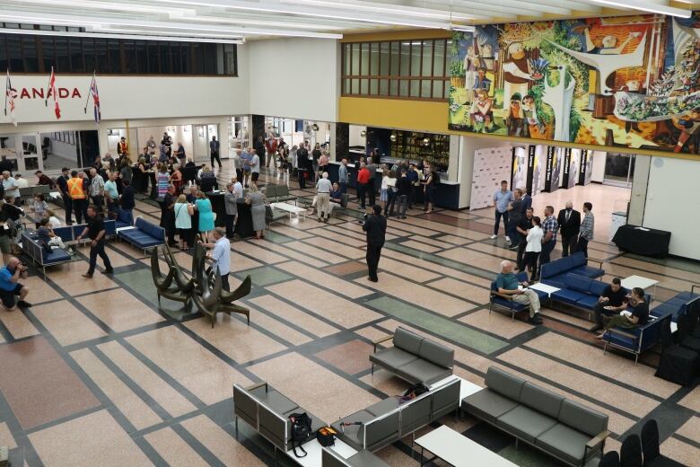 A large number of people gather in an airport lounge.