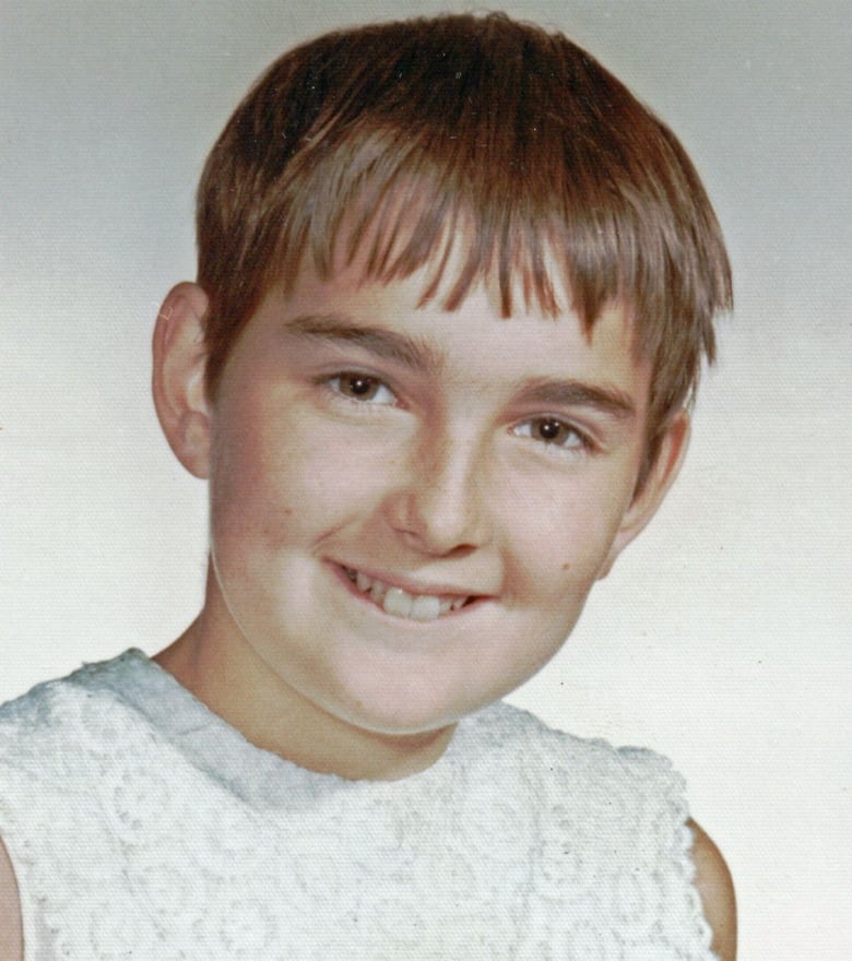 A young girl smiles with closely cropped hair.  