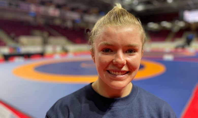 Smiling young woman stands in a wrestling gym. 