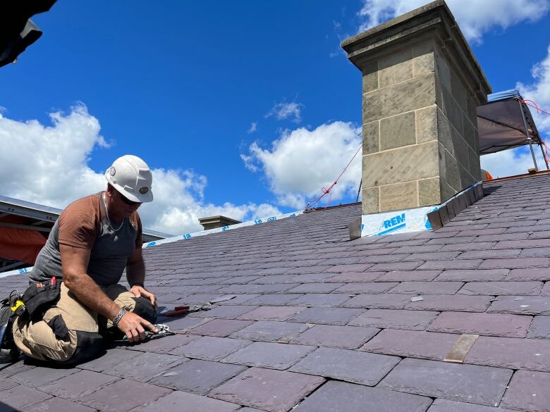 Worker on roof of large building.