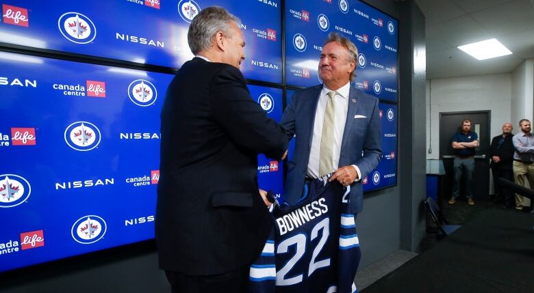 Two men are pictured shaking hands.