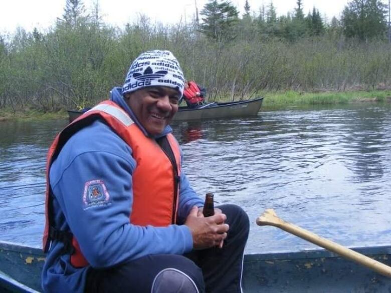 A man on a canoe, wearing life jacket, smiling