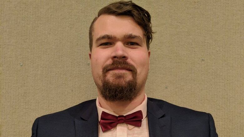 Close-up of a man with a neat beard and goatee, wearing a suit and bow tie.