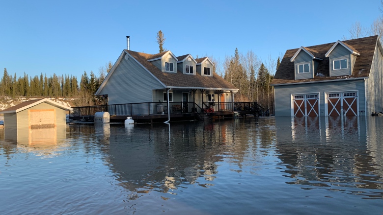 A house and gargage surronded by high water, nearly reaching the top of the house's front porch.