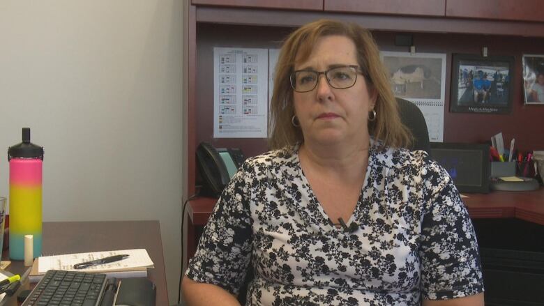 A woman sitting down in an office chair in an office.