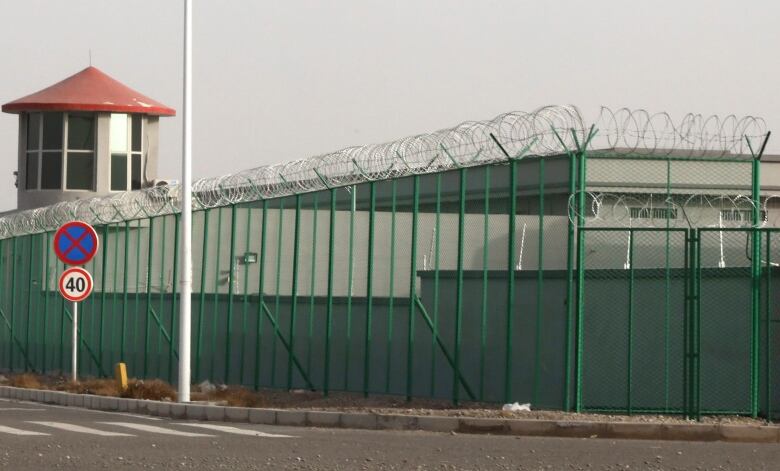 A guard tower, a fence and barbed wire surround a prison.