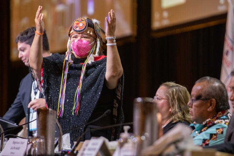 A politician rises with her hands in the air.