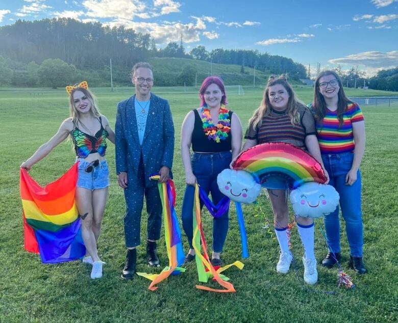 Five individuals with Temsikaming Pride hold rainbow flag and streamers.