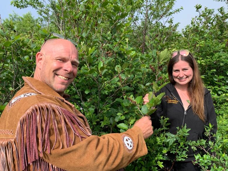 A man and woman in the woods on a sunny day looking at plants.