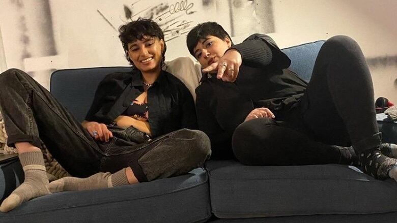 Two people pose on a couch.