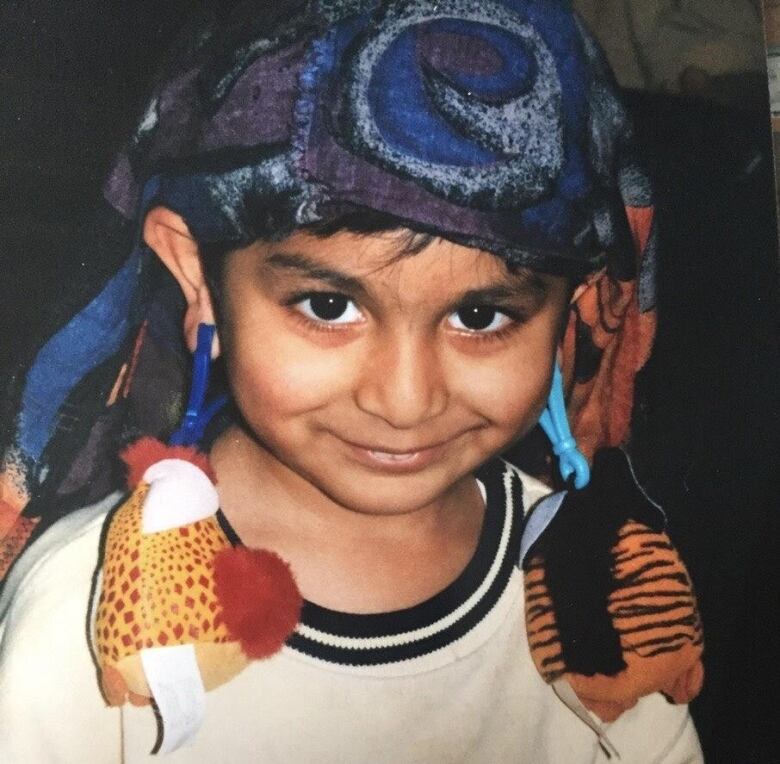 A young child wearing scarves and Furby keychains.