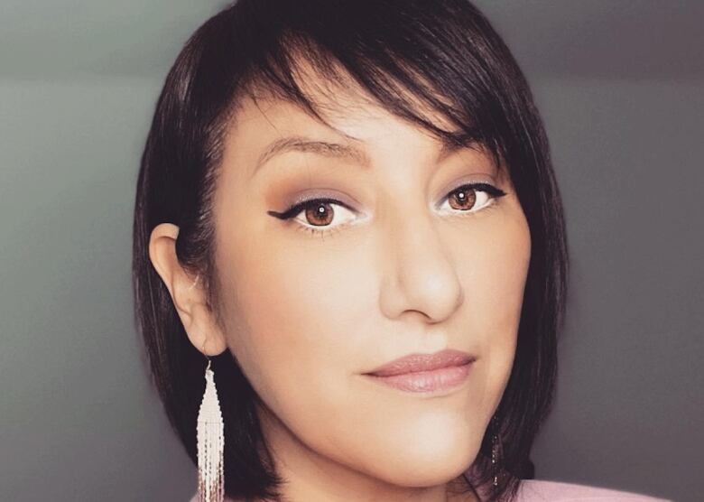 Close-up of woman with chin-length dark brown hair and brown eyes wearing pink blazer.