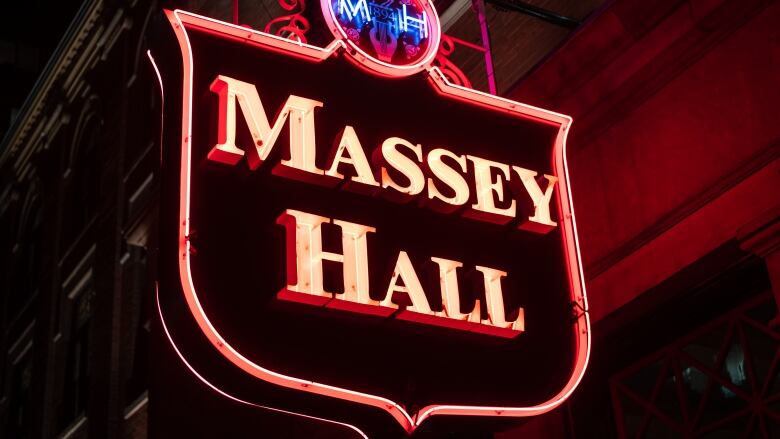 A neon sign, with the words Massey Hall illuminated in red, is pictured at night. 