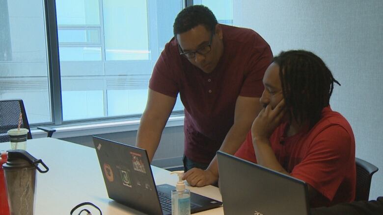 Two people looking at a laptop screen on a desk