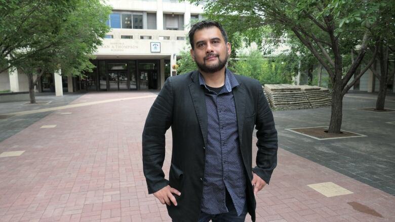 Man poses in front of city hall building.