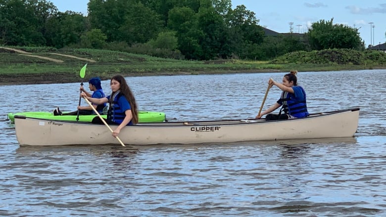 Two people paddle a canoe on a lake.