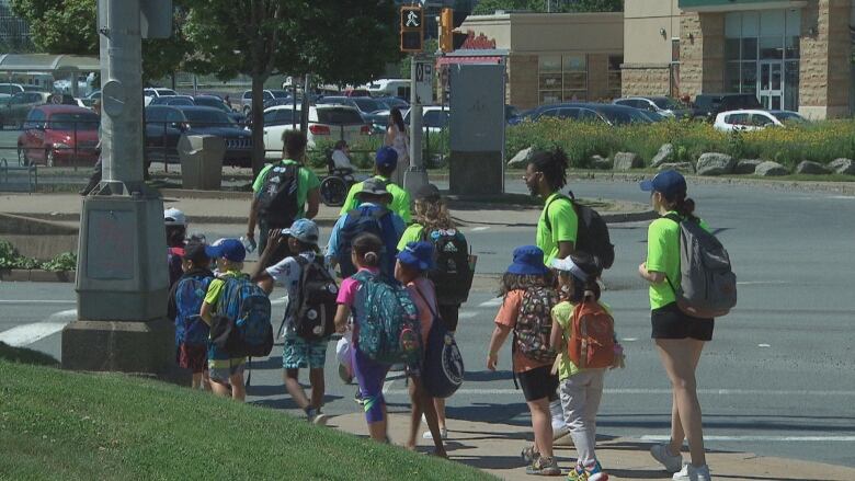 Camp staff escort children across a busy Halifax intersection.