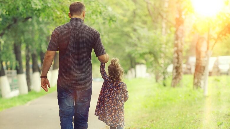 Man walks with young girl in a park.