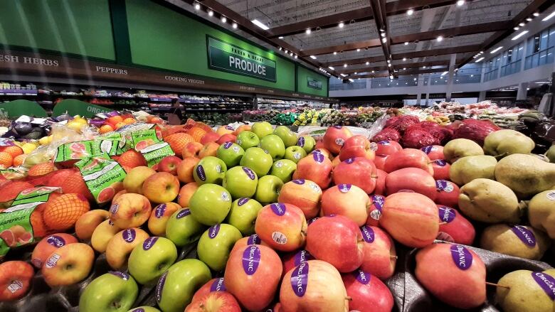 Piles of apples and oranges at a grocery store.