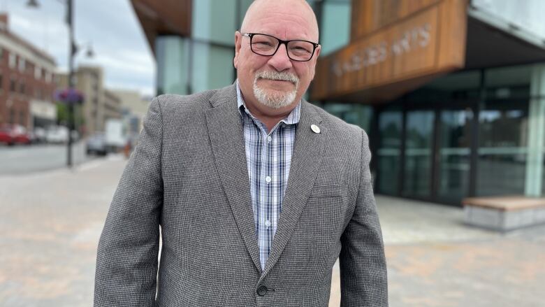 A middle aged man with glasses, wearing a suit jacket.