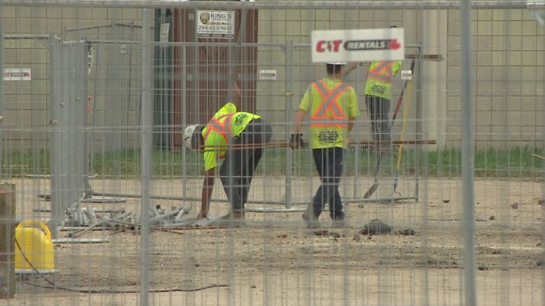 Workers installing construction fence.