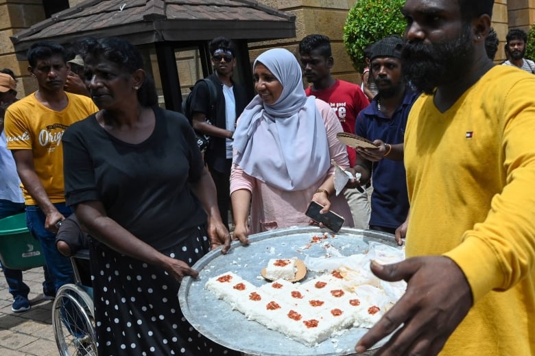 Several people hold a large tray of dessert treats.