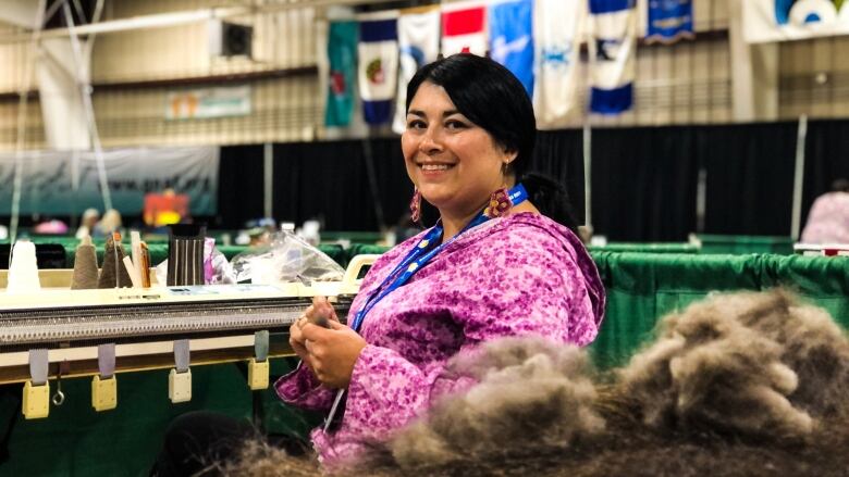 A woman smiles at the camera behind a pile of brown fibre.