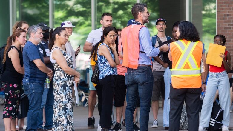 People waiting outside Montreal's Guy-Favreau complex listen to Service Canada employees.