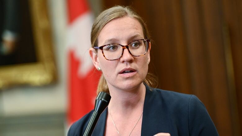 Woman stands before microphone in the House of Commons on Parliament Hill.