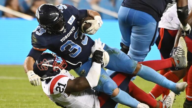 Toronto Argonauts running back Andrew Harris is tackled by Montreal Alouettes linebacker Chris Ackie during a game in Toronto Thursday, June 16, 2022.