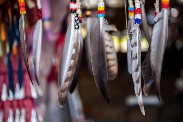 A series of feathers with Native markings and beads.