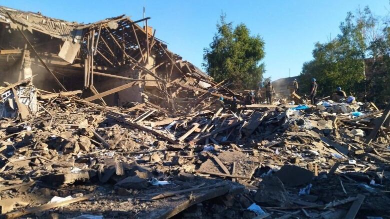 Piles of boards and debris in front of a destroyed building. 