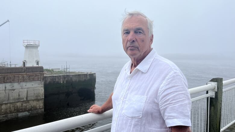 Man stands by railing overlooking harbour