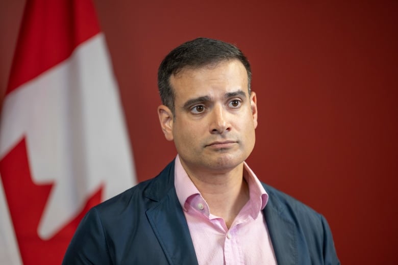 A man stands in front of a Canadian flag.