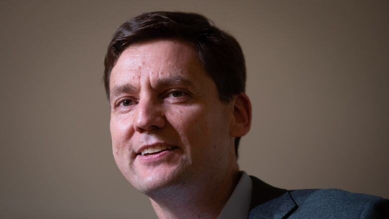 David Eby smiles, standing at a podium.