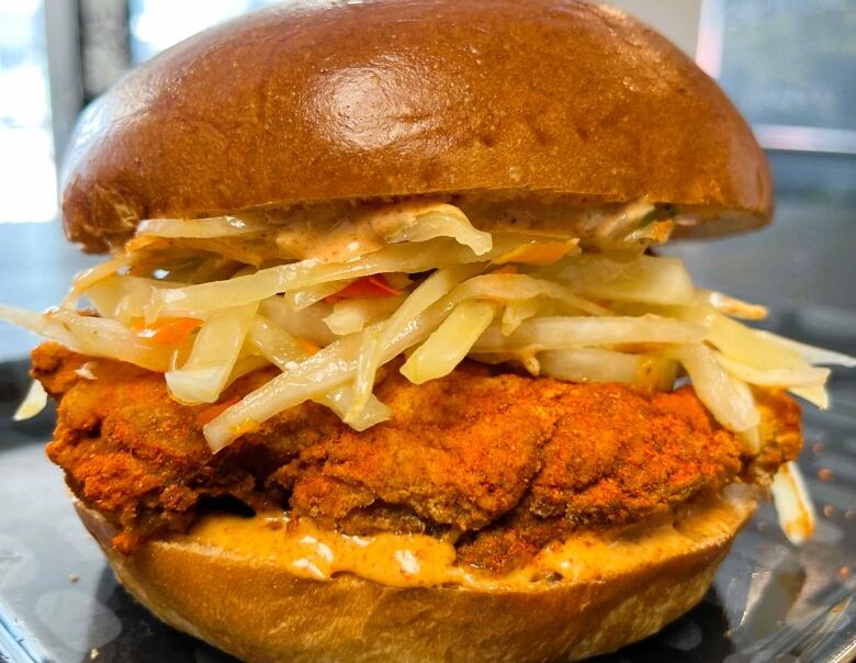 Fried chicken topped with coleslaw on a bun.