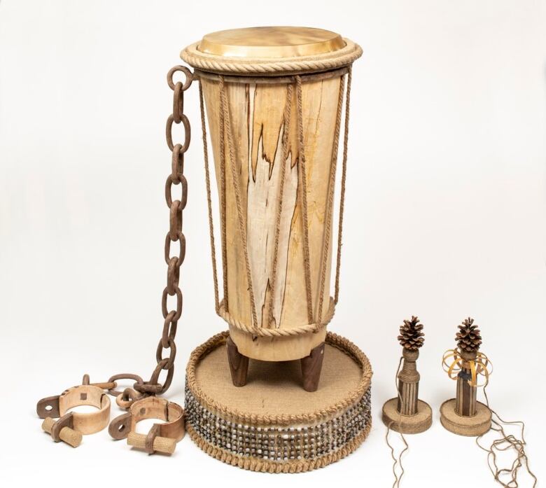 Photo of a tall wooden drum attached to a length of chain and manacles. 