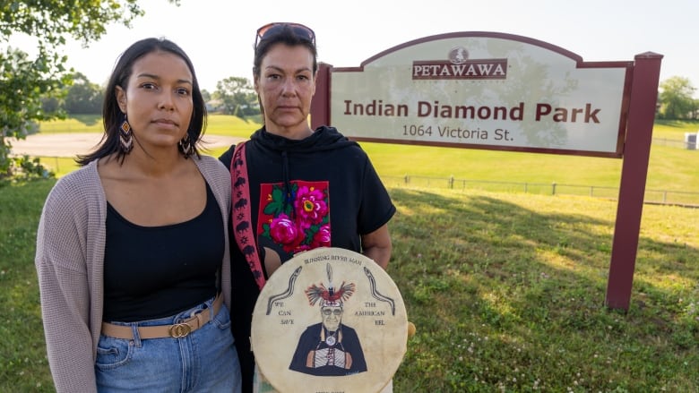 Two women stand in front of a sign that reads Indian Diamond Park.