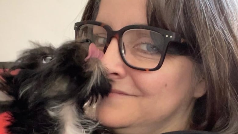 Woman holds dog as it licks her face.