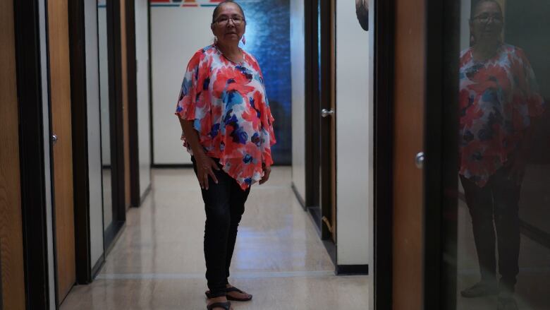 A woman stands in a hallway.