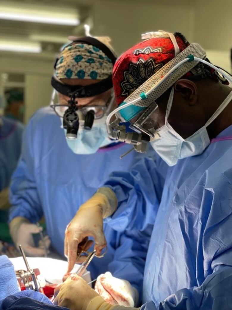 Two surgeons with head lamps performing heart surgery